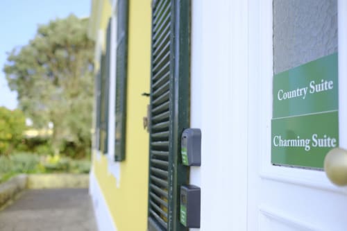 Charming Suite sign at Villa Várzea guesthouse in Várzea with yellow building and green shutters