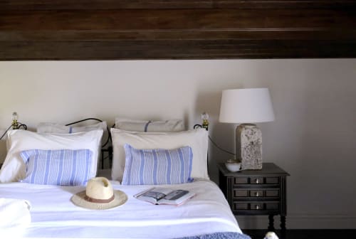 Country Suite bedroom at Villa Várzea with blue striped pillows, straw hat, bedside lamp, and dark wood nightstand in Várzea