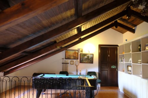 Attic game room at Villa Várzea with pool table, wooden beams, shelving, and rustic décor in Várzea, Portugal