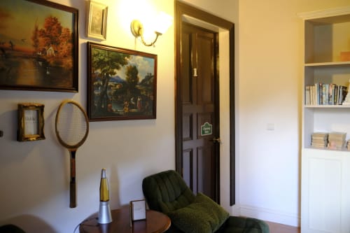 Charming Suite sitting area at Villa Várzea with vintage decor, green chair, framed artwork, and bookshelf in Várzea, PT