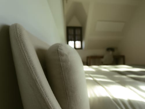 Fauteuil beige dans la chambre Colette à La Guirtelle, Lainsecq, avec vue sur le jardin et lumière naturelle