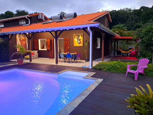 Villa Tourmaline Martinique, gîte avec piscine illuminée, patio coloré, salle à manger et chaise rose au crépuscule