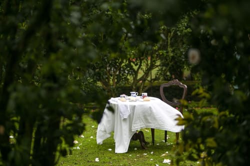 Intimate garden tea setting at Villa Várzea with white cloth-draped table and ornate chair surrounded by lush greenery in