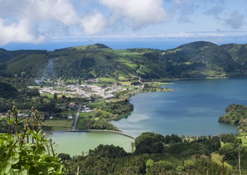 Aerial view of Villa Várzea nestled between two serene lakes surrounded by lush green mountains and forests in Portugal