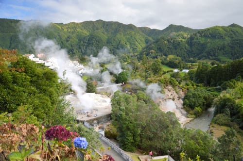 Geothermal valley view with steaming hot springs, lush green mountains, and Villa Várzea nestled in Várzea, Portugal