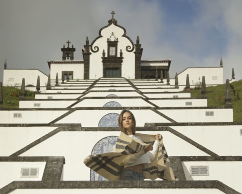 Woman at Villa Várzea holding scarf with Portuguese chapel and blue tile details in Várzea