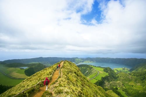 Hikers on mountain ridge overlooking green valleys and lakes near Várzea, Portugal from Villa Várzea