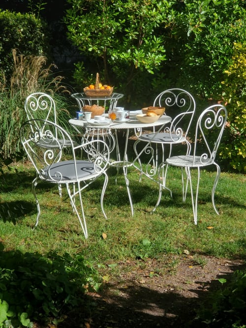 Mobilier de jardin en fer forgé blanc orné dans le jardin luxuriant du Logis des Tourelles, chambres d'hôtes à Cognac, France