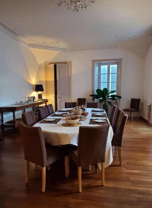 Élégante salle à manger du Logis des Tourelles avec table ronde, chaises marron et décoration classique.