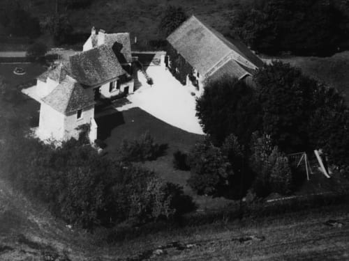 Aerial view of La Guirtelle B&B in Lainsecq, France, showing traditional architecture surrounded by trees