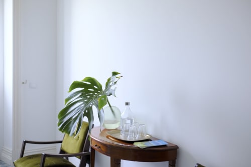 Minimalist room at Villa Várzea with Monstera plant, wooden side table, glasses, and water bottle in Várzea, Portugal