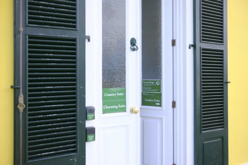 Villa Várzea entrance with green shutters, yellow walls, and suite directional signs in Várzea, Portugal