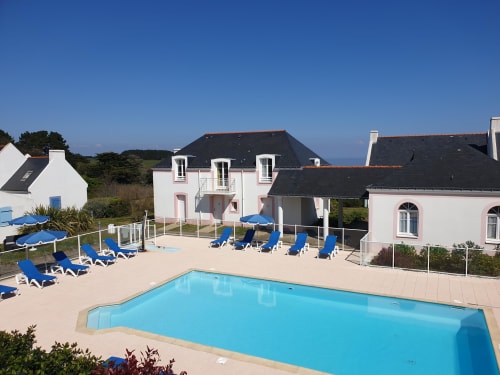 Piscine de la résidence avec transats bleus et appartements blancs à Locations Loc'Maria, Belle Île en Mer