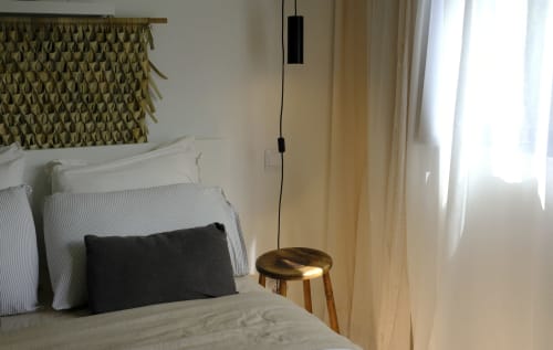 Modern bedroom at Villa Várzea Black Cabin with bed, black pendant light, wooden stool, and garden view through curtains