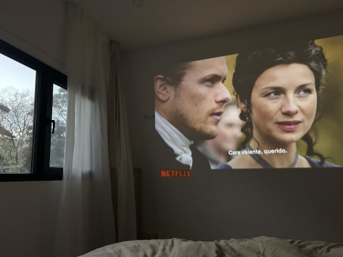 Netflix streaming on projector in Black Cabin bedroom at Villa Várzea with garden view and sitting area