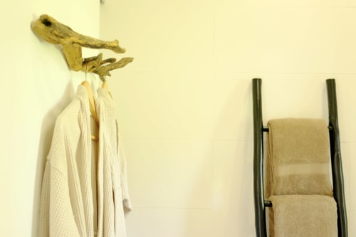 Rustic wooden bird-shaped hook with hanging white robe and black towel rack at Villa Várzea Black Cabin