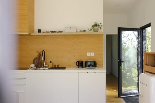 Modern kitchen with wooden backsplash, white cabinets, and garden views at Villa Várzea Black Cabin