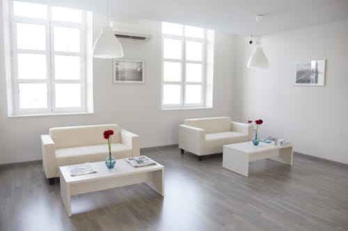 Recepción moderna del hotel Estació del Nord en Vic, Barcelona con sofás crema, mobiliario blanco y ventanales luminosos