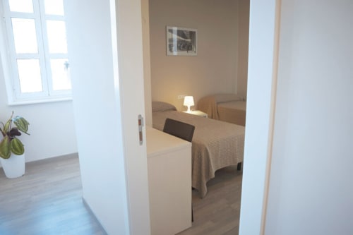 Entrada moderna de dormitorio en el hotel Estació del Nord de Vic, Barcelona, con cama, lámpara de noche y vistas luminosas por la ventana