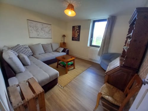 Salon contemporain à La Maison De Fleurat à Domeyrot avec canapés gris, mobilier bois et lumière naturelle