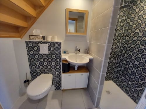 Salle de bain moderne à La Maison De Fleurat à Domeyrot, avec carrelage géométrique, lavabo blanc, toilettes et douche à l'italienne.