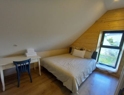 Chambre sous les toits à La Maison De Fleurat avec lit queen-size, bureau et fenêtre sur la campagne de Domeyrot