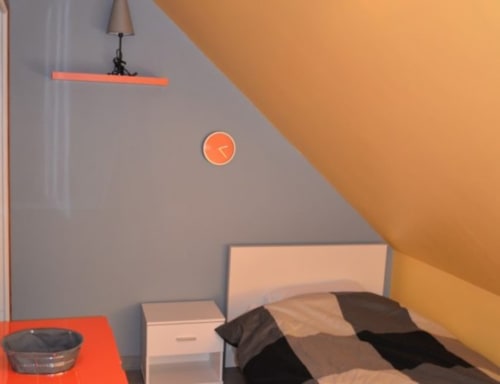 Chambre mansardée contemporaine à l'hôtel Mape de Dampierre en Burly avec mur d'accent orange et décoration minimaliste