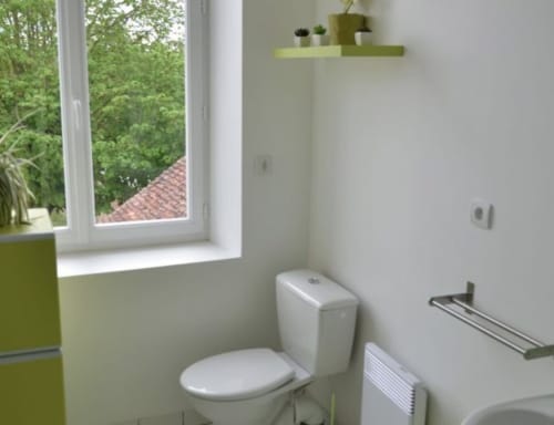 Salle de bains moderne à l'hôtel Mape à Dampierre-en-Burly avec toilettes, lavabo, fenêtre sur la verdure et accents vert citron