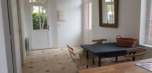 Intérieur d'appartement moderne et lumineux avec table à manger noire, chaises en bois et vue sur le jardin à l'hôtel Les Cabines à Houlgate