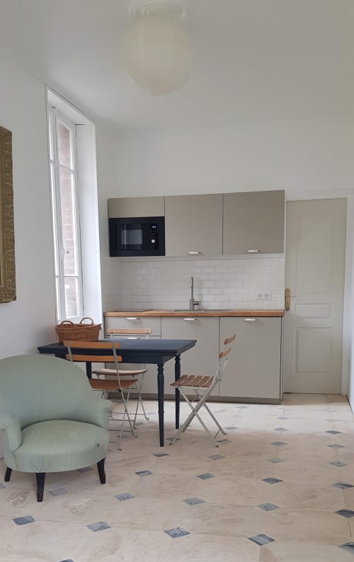 Cuisine et salle à manger modernes de l'appartement Les Cabines à Houlgate, table noire, meubles beiges, vue sur jardin