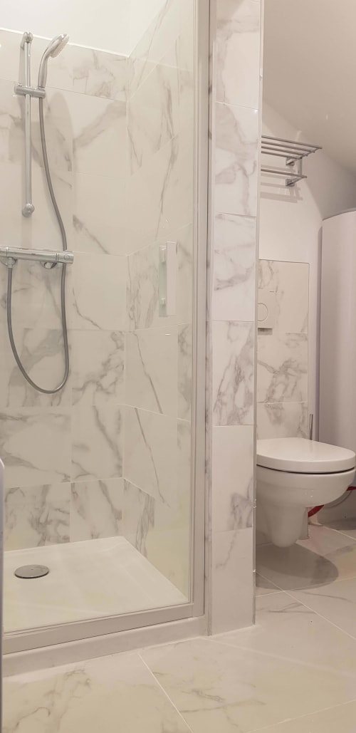 Salle de bain moderne avec douche en marbre et toilettes blanches à l'appartement-hôtel Les Cabines à Houlgate