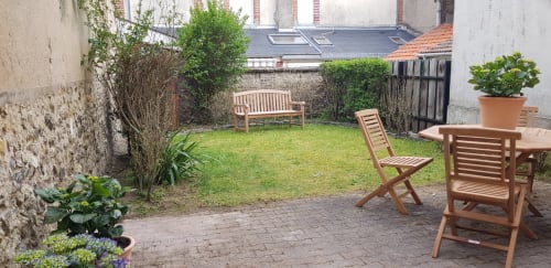 Patio jardin privé des Cabines à Houlgate avec mobilier en bois et verdure luxuriante