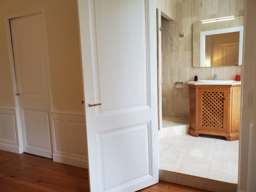 Entrée de la chambre Bassac au Logis des Tourelles avec portes en bois, moulures blanches et salle de bains attenante avec vanité en bois à Cognac