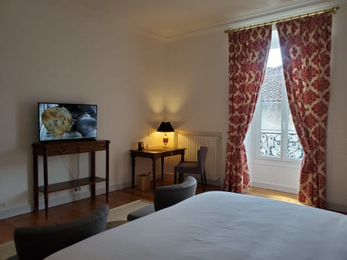 Chambre élégante aux Logis des Tourelles à Cognac avec vue sur la ville, télévision, bureau et rideaux damassés rouges