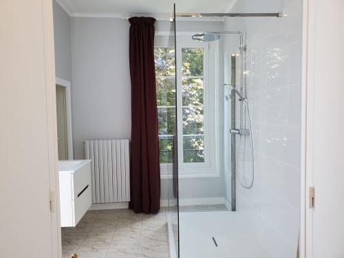 Salle de bain moderne au Logis des Tourelles à Cognac avec douche à l'italienne, radiateur chauffant et fenêtre avec vue sur la ville