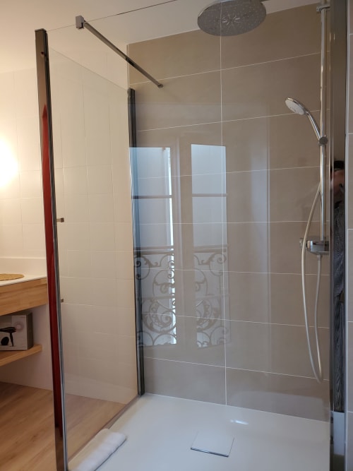 Douche moderne avec paroi vitrée et pomme de douche effet pluie au Logis des Tourelles à Cognac