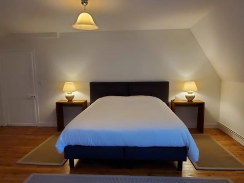 Moderne slaapkamer bij Logis des Tourelles in Cognac met blauw dekbed, zwart hoofdeinde, nachtkastjes, lampen en houten vloeren