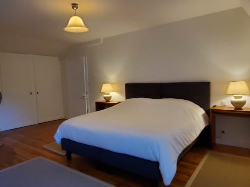 Ruime slaapkamer in Logis des Tourelles in Cognac met queensize bed, nachtkastjes, lampen en houten vloer