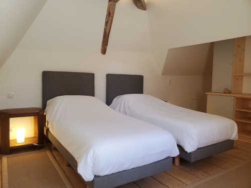 Twee eenpersoonsbedden met witte lakens in appartement Bouteville bij Logis des Tourelles, Cognac, met houten balken en tuinuitzicht
