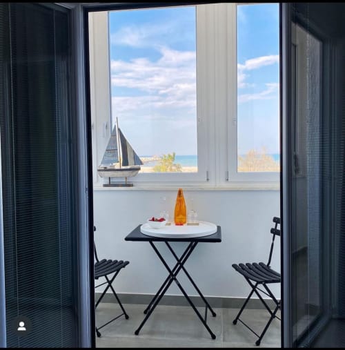 Vista dal balcone di B&B Dimora Vistamare a Barletta con vista mare, tavolino, sedie e decorazione di vela che si affaccia su