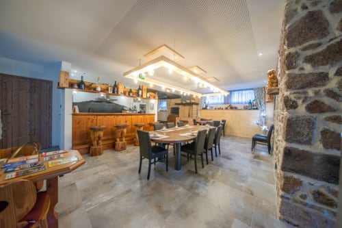 Espace cuisine-salle à manger ouvert à la Villa Valtin B&B au Valtin avec murs en pierre, bar en bois et luminaires modernes