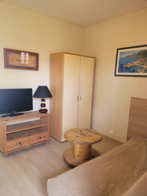 Appartement corse douillet avec mobilier en bois, TV, salon et table ronde en bois avec vue sur la mer