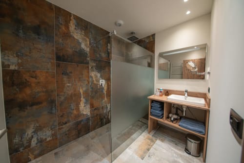 Salle de bain moderne à la Villa Valtin avec douche aux carreaux de cuivre rustique, meuble vasque en bois et miroir au Valtin, France