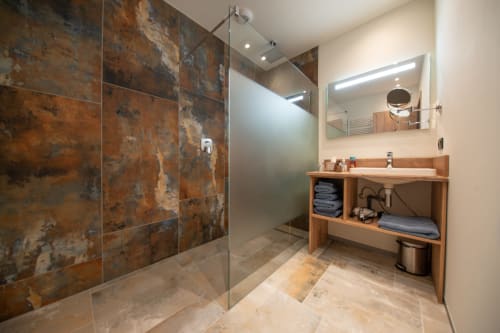 Salle de bain moderne à la Villa Valtin avec douche carrelage effet cuivre rustique, meuble vasque en bois et miroir chauffant éclairé