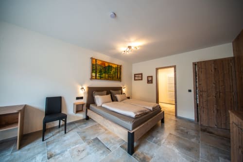 Chambre spacieuse à la Villa Valtin B&B au Valtin avec lit en bois, vue montagne, équipements modernes et sol en pierre