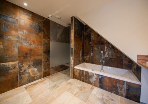 Salle de bains luxe moderne à la Villa Valtin avec carrelage cuivre rustique, douche à l'italienne, baignoire îlot et sol chauffant