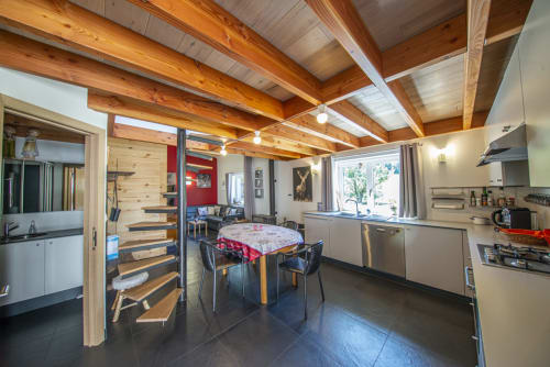 Intérieur ouvert du cottage Villa Valtin avec poutres apparentes, table à manger, cuisine et vue sur les montagnes