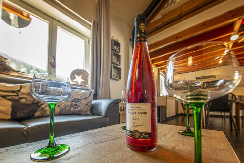 Bouteille de Pinot Noir avec verres à tige verte sur table en bois à la Villa Valtin en Alsace, vue sur les montagnes