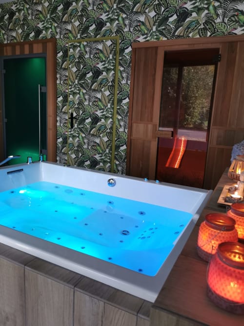 Spa luxueux avec bain à remous illuminé de LEDs bleues à La Cour d'Hortense, décor tropical et vue sur le jardin