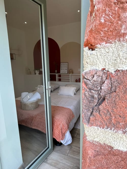 Chambre La Cour d'Hortense avec lit queen-size, accents bourgogne, miroir arqué et vue sur le jardin à Sailly-Flibeaucourt